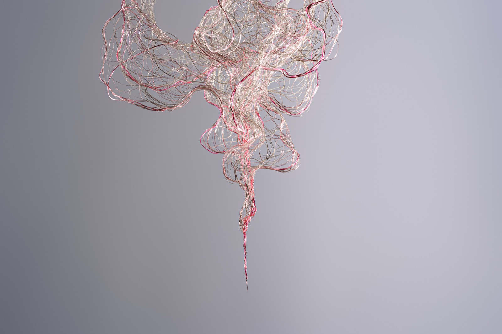 Wisps and Whispers, a suspended wire sculpture with pink and silver strands against a grey background.